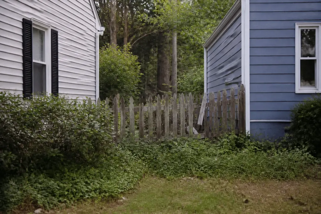Deux maisons avec clôture bois usée entre propriétés voisines