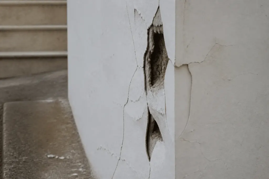 Mur blanc avec trous profonds et fissures visibles