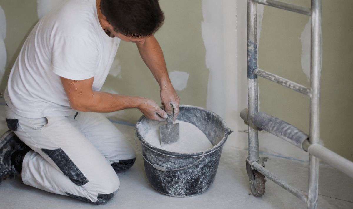 Homme melangeant poudre blanche dans seau avec spatule