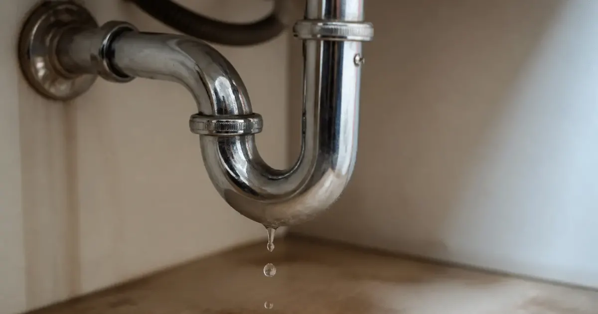 Tuyauterie metallique sous evier avec gouttes d'eau tombant vers le sol