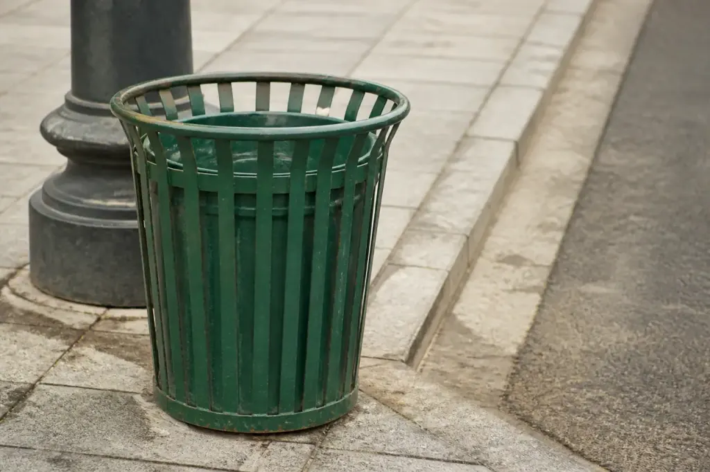 Benne metallique verte posee sur un trottoir
