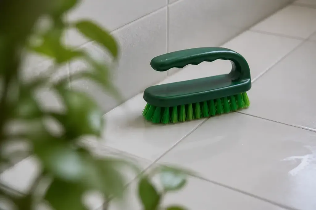 Brosse verte nettoyant carrelage blanc de salle de bains