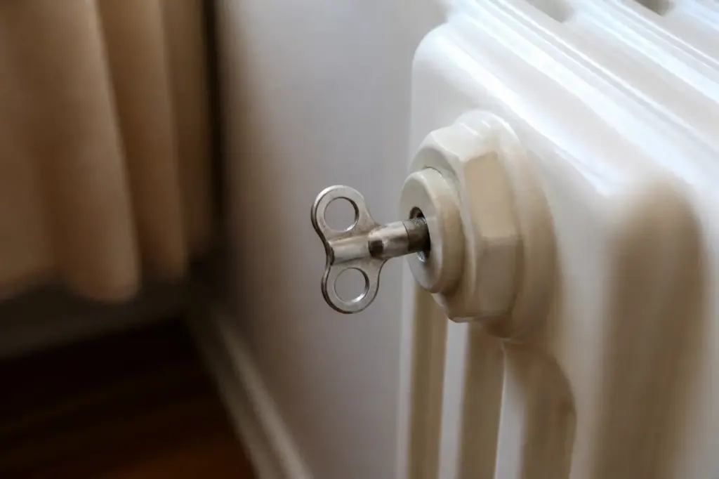 Main tenant une cle de purge sur un radiateur
