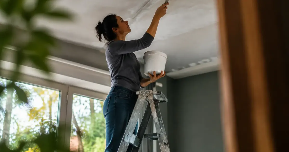 Une femme debout sur une echelle isole un plafond