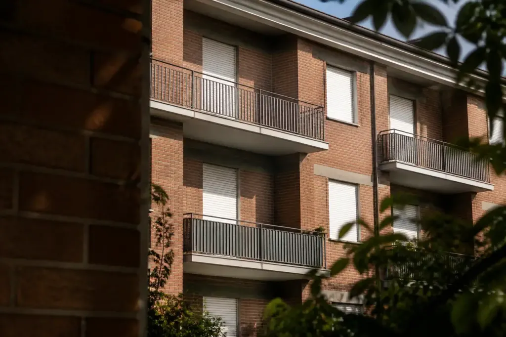 Immeuble social en brique avec balcons et volets fermes