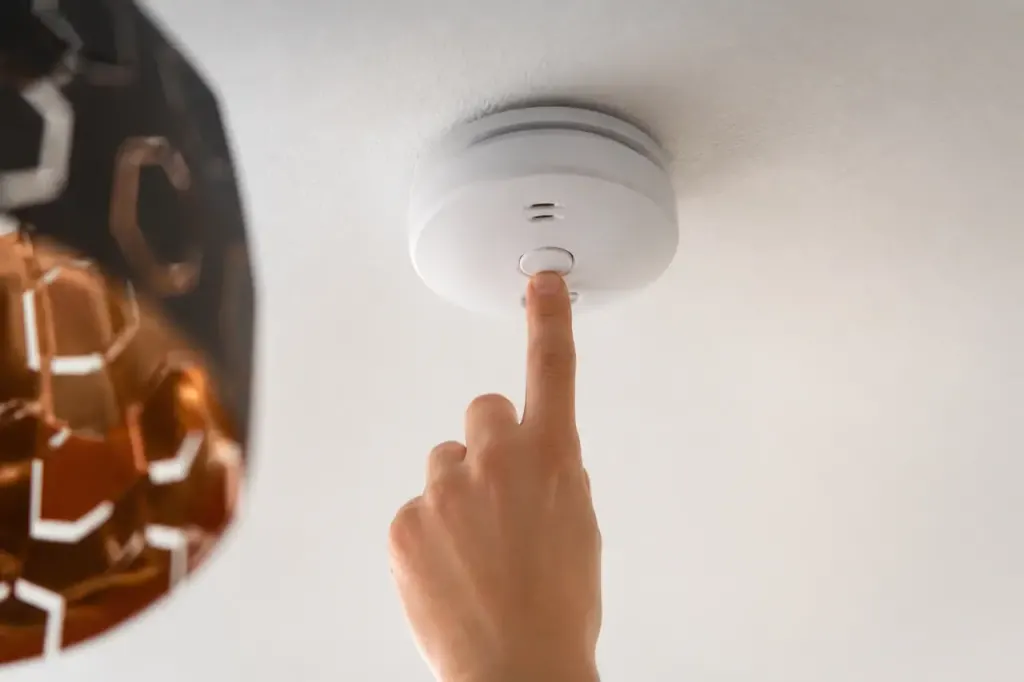 Main appuyant sur bouton test blanc au plafond