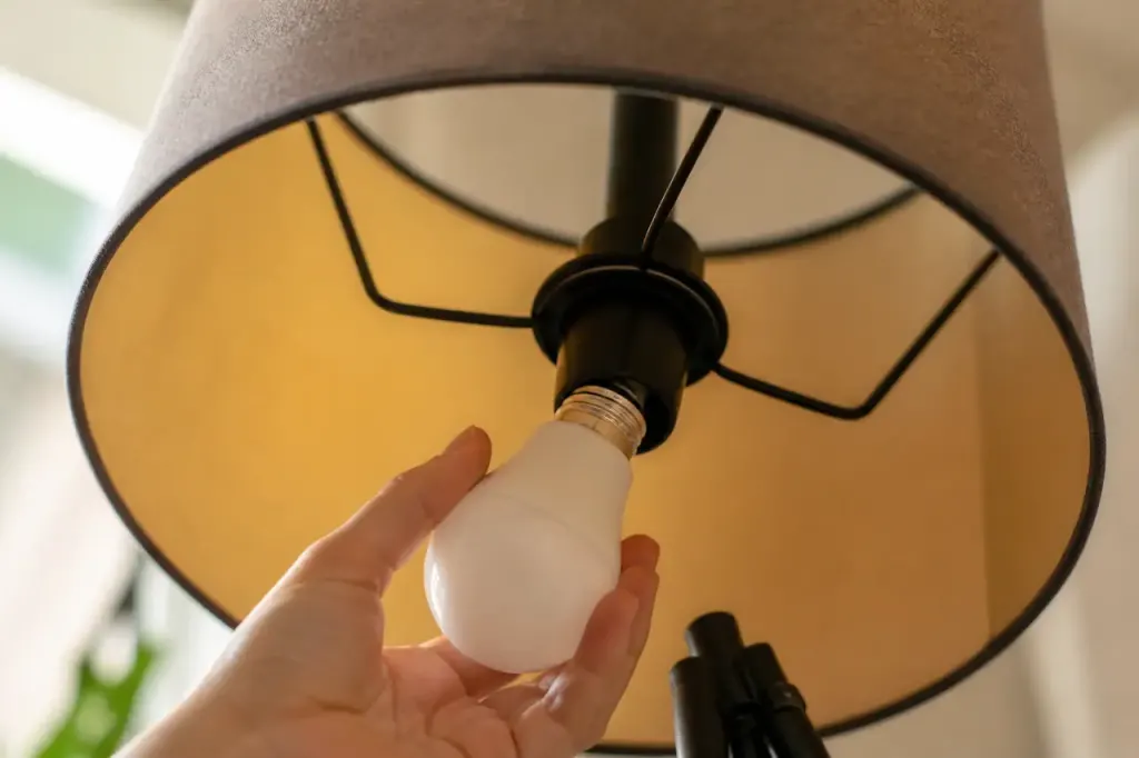 Main vissant une ampoule LED blanche sur lampe