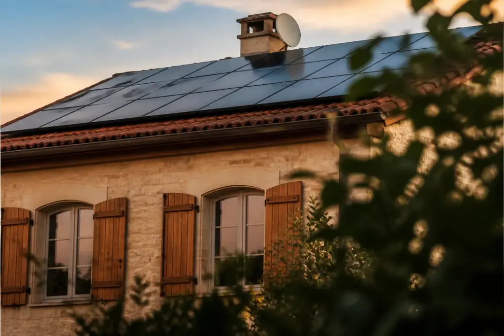 Maison avec volets bois et panneaux solaires sur toit