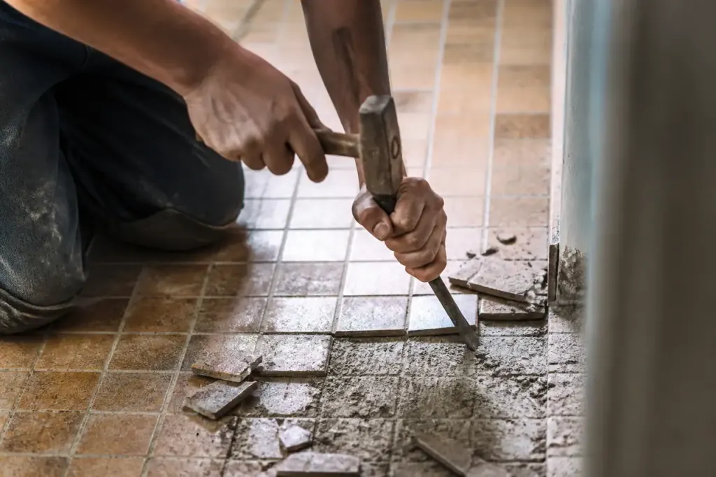 Ouvrier retirant carreaux fissurés au burin