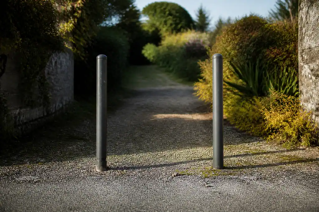 Poteaux métalliques barrant un chemin entre deux jardins